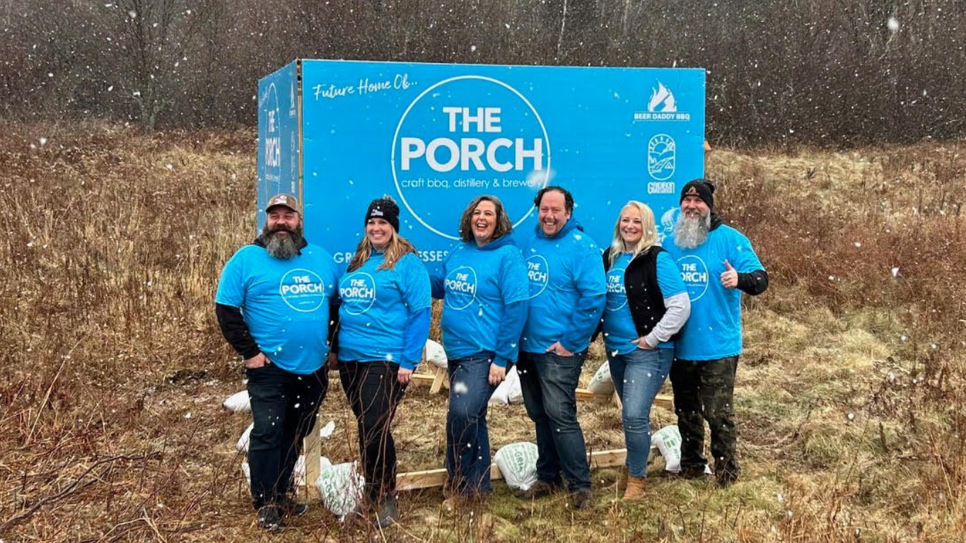 six people standing infront of sign that reads The Porch 