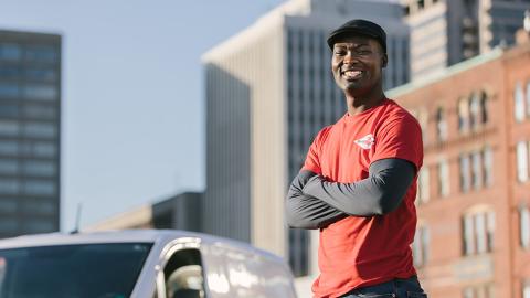 man smiling in front of car