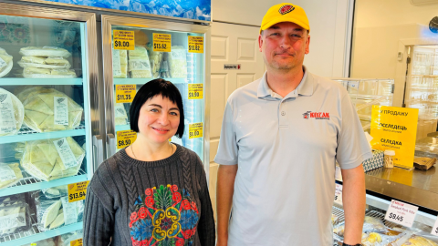 couple standing in front of refrigerators smiling 