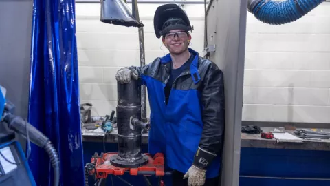 man standing in welding shop smiling at camera