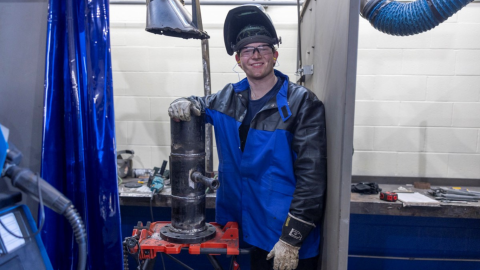 man standing in welding shop smiling at camera