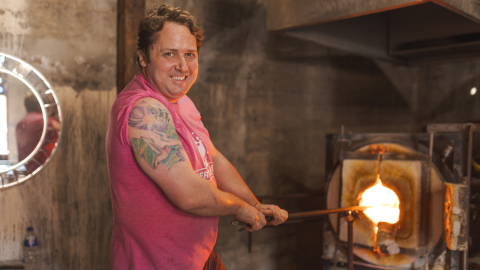 man smiling at camera blowing glass 